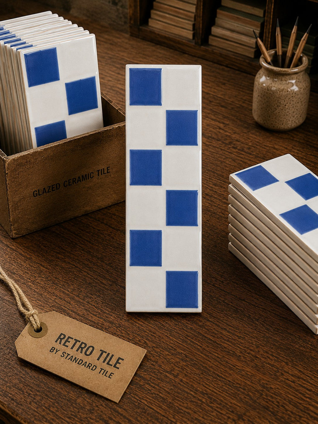 Retro Tile by Standard Tile blue and white checkerboard ceramic accent tile with a glossy finish on a wooden desk.